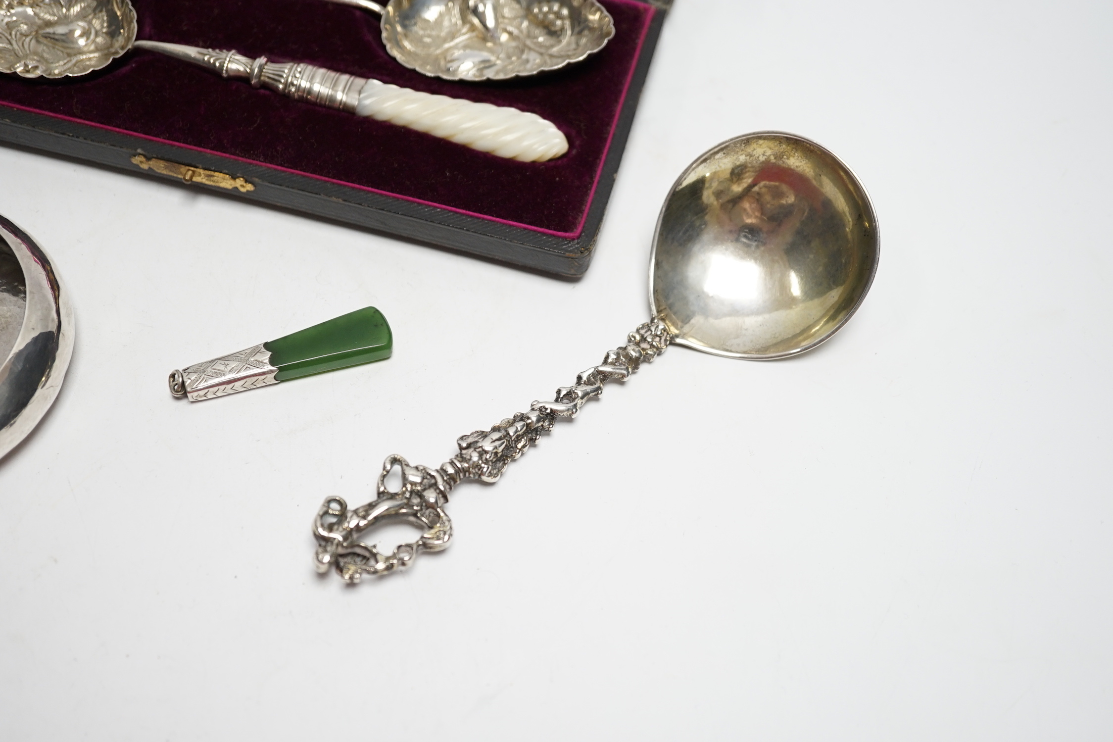 A cased pair of late Victorian mother of pearl handled silver 'berry' spoons, by A.J. Bailey, Birmingham, 1896, a continental white metal spoon with figural terminal, a pierced white metal sugar basket, with blue glass l